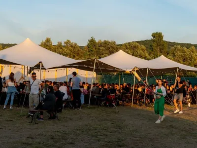 Stretch tent set up for a vibrant outdoor festival, providing shade and shelter for attendees at the event.
